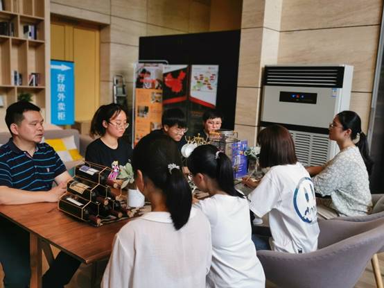 一群人坐在桌子前描述已自动生成 一群人坐在桌子前描述已自动生成